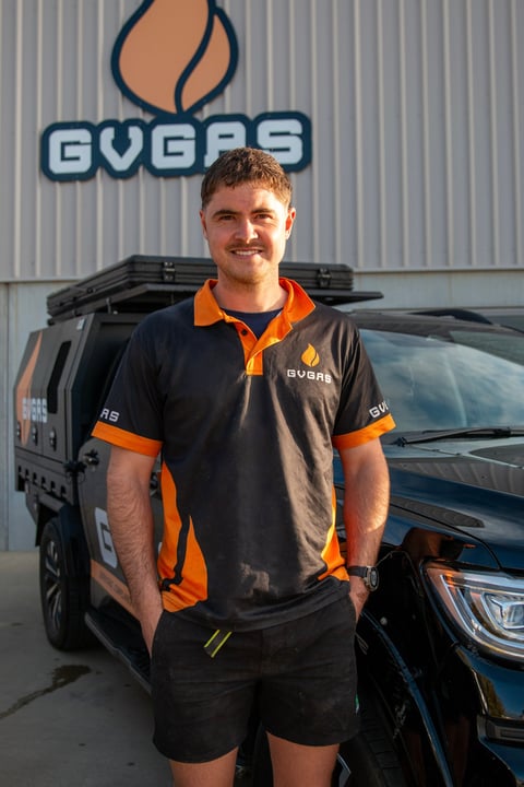 Man in GVBRS uniform standing in front of work van with company logo on warehouse wall